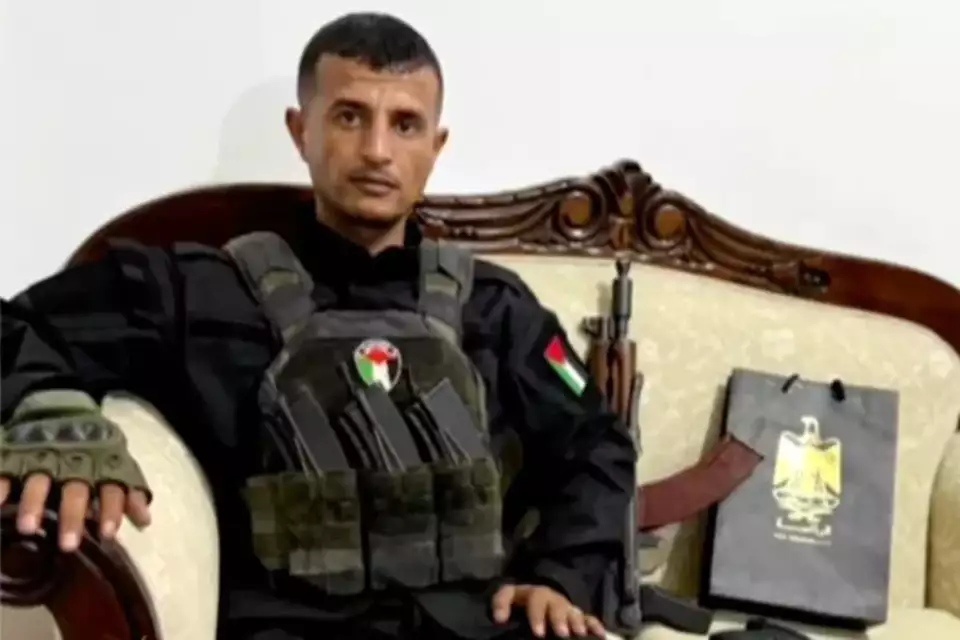 Israels Sicherheitspolitik Strategische Herausforderungen im Gaza Libanon und Syrien 4 Bewaffneter Mann in schwarzer Uniform mit palästinensischen Abzeichen auf einem Sofa, daneben ein Gewehr und eine Tasche mit PA-Wappen.